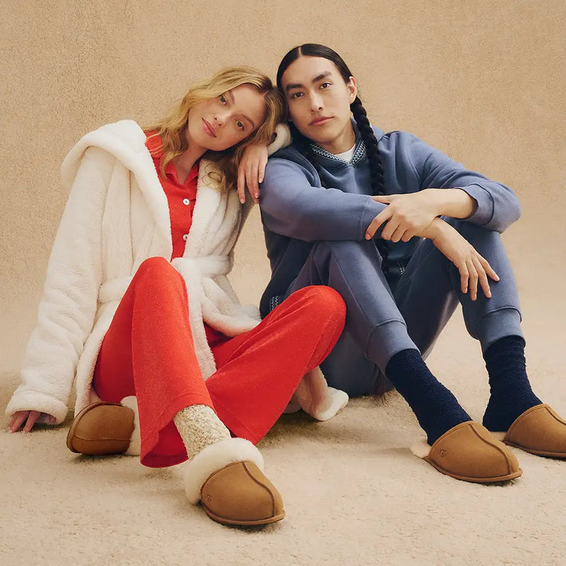 Tan ugg slip-on mules with plush white shearling lining and a soft suede exterior.
